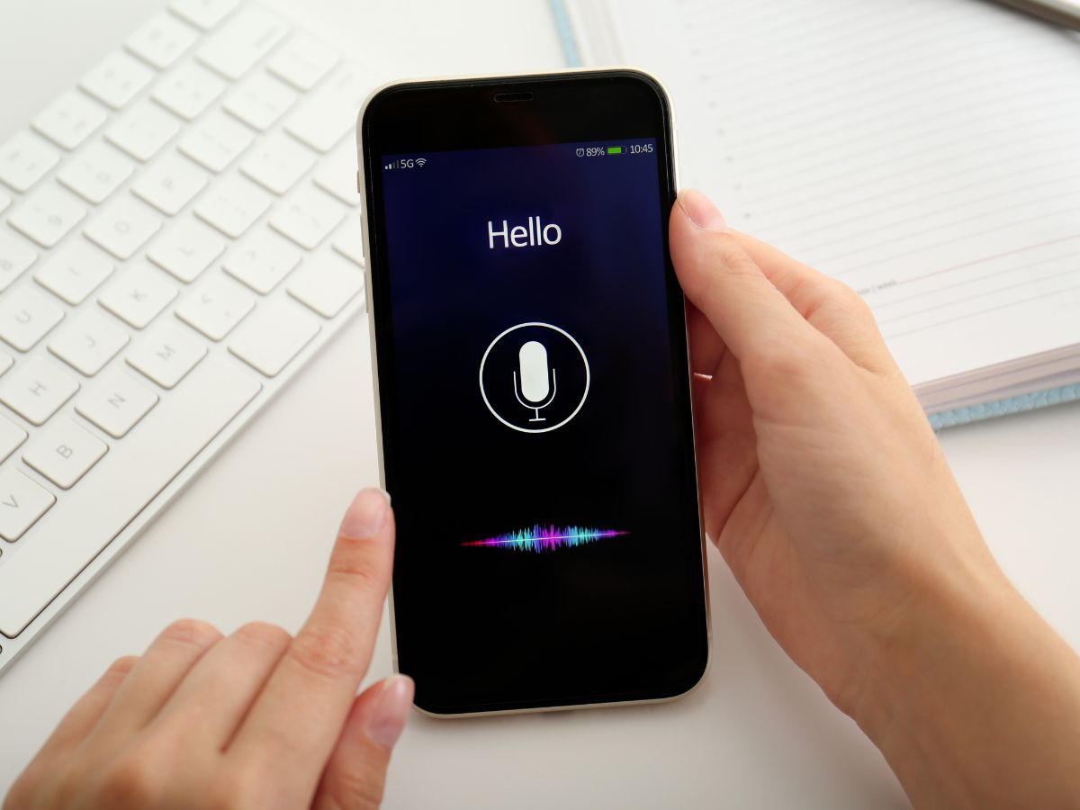 A person using voice search on a smartphone, with a microphone icon on the screen.