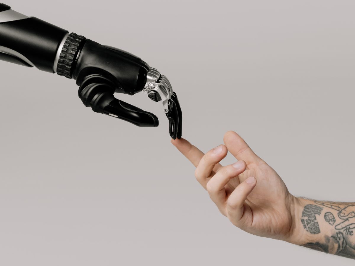A robotic hand and a human hand reaching out.