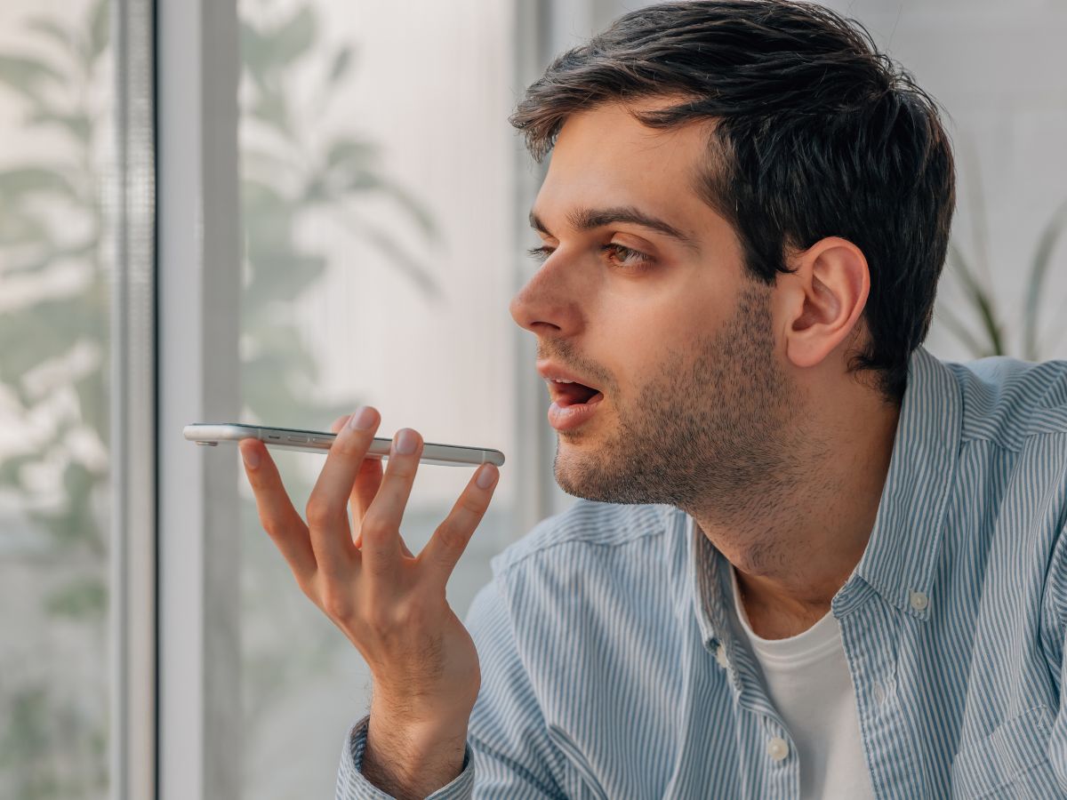 A man speaking into his smartphone, using voice search in a modern setting.