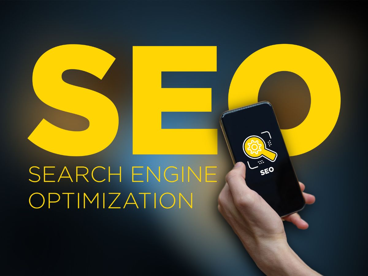 A hand holding a phone with "SEO" on the screen, large yellow text in the background.